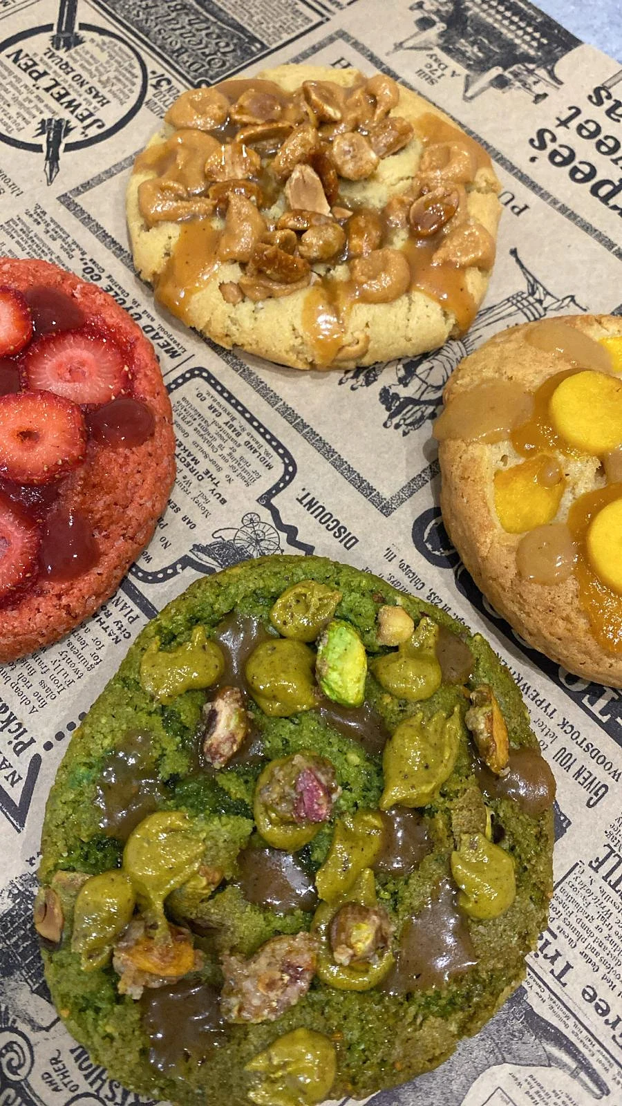 Quatre cookies décorés présentés sur un papier imprimé
