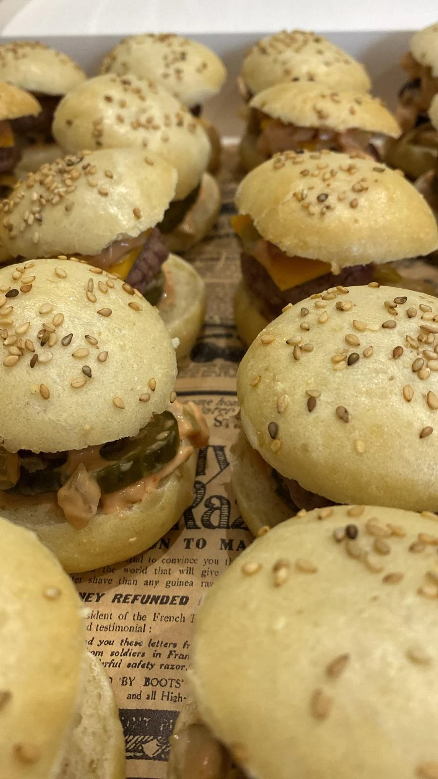 Mini cheeseburgers au pain sésame présentés dans une box